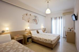a hotel room with two beds and a television at Hippocampus Hotel in Kamari