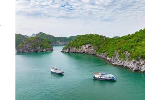 two boats in a large body of water with cliffs at Nhật Anh Hotel Cát Bà in Cat Ba