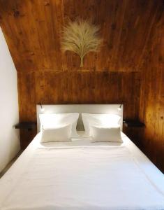 a bedroom with a white bed with a wooden headboard at Vrleti Tare in Bajina Bašta