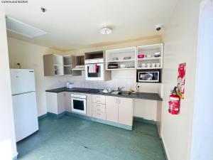 a kitchen with white cabinets and a white refrigerator at Stay Hostel Rotorua in Rotorua