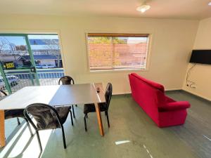 een eetkamer met een tafel en een rode stoel bij Stay Hostel Rotorua in Rotorua