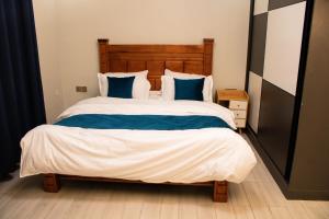 a bedroom with a large bed with blue pillows at C&C Apartment at Kileleshwa in Nairobi