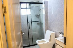 a bathroom with a toilet and a glass shower at C&C Apartment at Kileleshwa in Nairobi