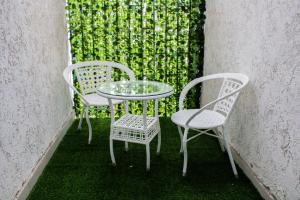 2 stoelen en een glazen tafel en stoelen op een patio bij C&C Apartment at Kileleshwa in Nairobi