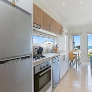 a kitchen with white appliances and a dining room at Anlyn seaside cabin in Apollo Bay