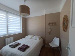 een slaapkamer met een wit bed en een witte stoel bij chez Clem in Calais