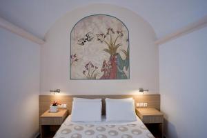 a bedroom with a bed and a painting on the wall at Hippocampus Hotel in Kamari