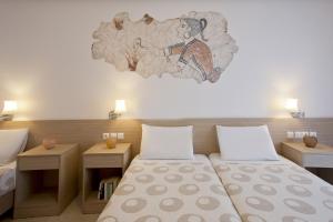 a room with two beds and a painting on the wall at Hippocampus Hotel in Kamari