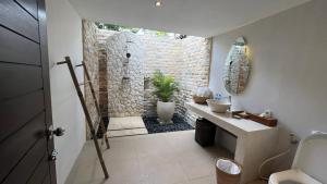 a bathroom with a stone shower and a sink at Living Asia Resort and Spa in Senggigi