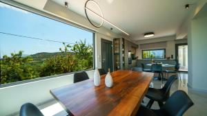 a dining room with a table and a large window at Mythic Olive villa - Heated Pool - Amazing view in Perivólia