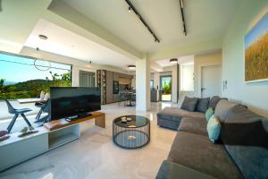 ein Wohnzimmer mit einem Sofa und einem TV in der Unterkunft Mythic Olive villa - Heated Pool - Amazing view in Perivólia