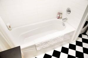 a white bath tub in a bathroom with a checkered floor at Historic Charm in Victoria BC's Waddington Alley in Victoria