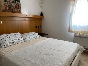a bedroom with a white bed with a wooden headboard at La casa degli Ibiscus in Porto Ottiolu