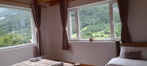 a bedroom with two beds and two large windows at Guesthouse Dritan Tethorja in Theth