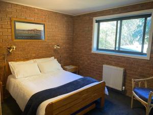 1 dormitorio con cama y pared de ladrillo en LimLimBu 12, en Falls Creek