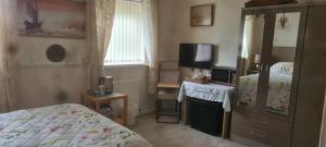 a small bedroom with a bed and a dresser at Parc Lodge Guesthouse in Bridgend