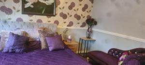 um quarto com uma cama roxa e um sofá em Parc Lodge Guesthouse em Bridgend