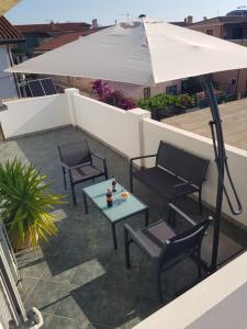 une terrasse avec une table, des chaises et un parasol dans l'établissement Tortolì attico in centro a 5 minuti dal mare, à Tortolì