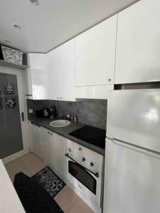 a white kitchen with a sink and a refrigerator at Magnifique 2 pièces, jardin et parking in Saint-Laurent-du-Var