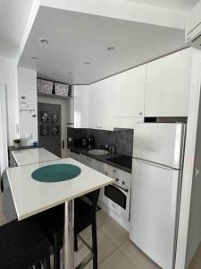 a kitchen with white cabinets and a table with chairs at Magnifique 2 pièces, jardin et parking in Saint-Laurent-du-Var