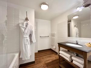 La salle de bains blanche est pourvue d'un lavabo et d'une baignoire. dans l'établissement Hôtel des Basses Pyrénées - Bayonne, à Bayonne
