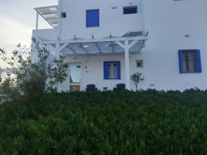 a white building with blue windows on top of a green field at Maistrali in Provatas