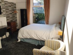 a bedroom with a bed and a chair and a window at Lyndene House in Huddersfield