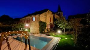a villa with a swimming pool in front of a building at Le couvent de Jouels in Sauveterre-de-Rouergue