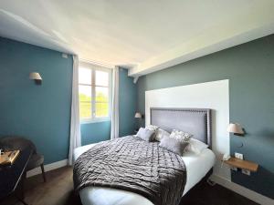 a bedroom with a bed with blue walls and a window at Hôtel des Basses Pyrénées - Bayonne in Bayonne