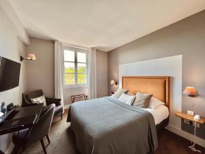 a bedroom with a bed and a desk and a computer at Hôtel des Basses Pyrénées - Bayonne in Bayonne