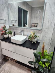 uma casa de banho com lavatório, espelho e plantas em Bed & Breakfast @ Unsworth Heights Albany em Auckland