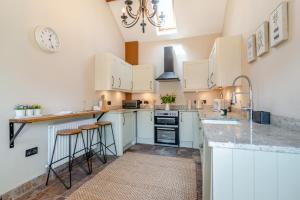 a kitchen with white cabinets and a counter with stools at The Old Moat Barn - With Private Hot Tub in Stockton-on-Tees