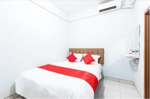 uma cama com almofadas vermelhas num quarto branco em Hotel Cemara Gading em Bubulak 3