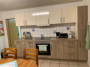 a kitchen with white cabinets and a stove top oven at kleines Ostfriesenhaus mitten im Grünen, Mindestaufenthalt 3 Tage, bitte vorher anfragen in Osteel
