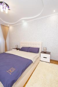 1 dormitorio con 1 cama grande y 2 mesitas de noche en Центр. Хмельницького. 2 спальні, en Ternopilʼ