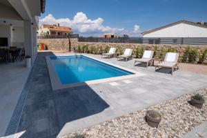 una piscina con sillas y una mesa en Holiday house JEWEL with private pool, en Kornić
