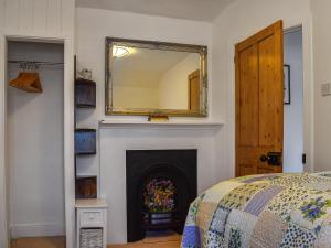 a bedroom with a fireplace with a mirror over it at Chapel House in Bourton on the Water