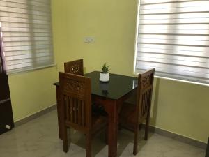 a dining room table and chairs in a room with windows at Gods own home stay in Cochin