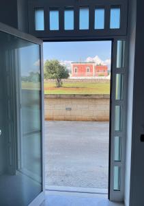 une porte en verre ouverte avec vue sur un bâtiment dans l'établissement Dimora Azzurra, à Pezze di Greco