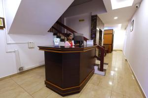 una mujer sentada en un mostrador en una habitación en VKG Hotels en Pondicherry