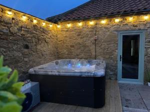 uma grande banheira sentada num pátio com luzes em The Old Moat Barn - With Private Hot Tub em Stockton-on-Tees