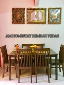 a dining room table with chairs and a sign on the wall at Am Homestay Rembau in Rembau