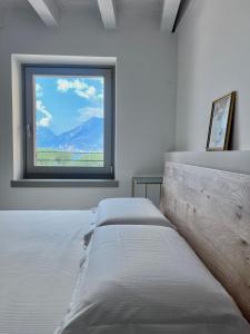 two beds in a room with a window at Absentia 1763 Garda Boutique Home - Lake front in Brenzone sul Garda