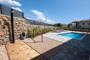 un patio trasero con piscina y pared de piedra en Holiday house JEWEL with private pool, en Kornić