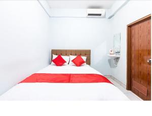 a bed with red pillows in a white room at Hotel Cemara Gading in Bubulak 3