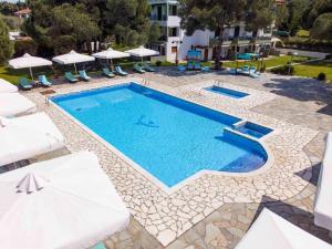 a swimming pool with chairs and umbrellas next to a building at Alexandros Hotel Apartments in Vourvourou