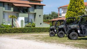 two utility vehicles parked in front of a building at Alexandros Hotel Apartments in Vourvourou