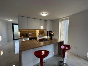 a kitchen with a counter and two red stools at GRAND HYATT APPARTMENTS in Podhájska