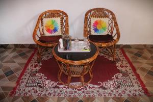 3 sillas y una mesa con una bandeja en una alfombra en Infinity Hill Village Mukteshwar, en Mukteshwar