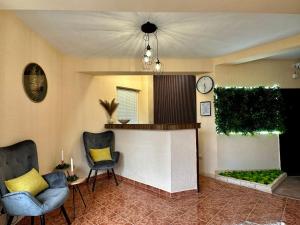 a living room with two chairs and a clock on the wall at Amirov Garden - Free parking & Free beach area in Kranevo